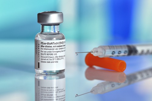 Pfizer COVID-19 vaccine next to syringe