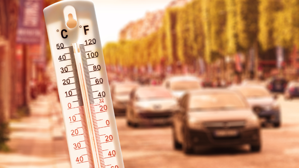 A thermometer in front of blurred cars on a busy road