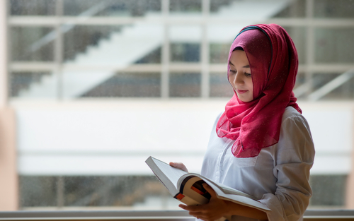 Woman in hijab smiling while reading