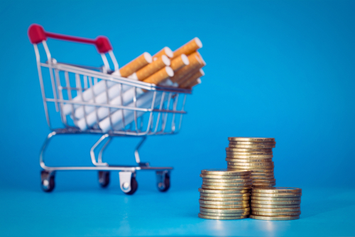 Health taxes portrayed as cigarettes in a shopping cart with stacks of coins next to it