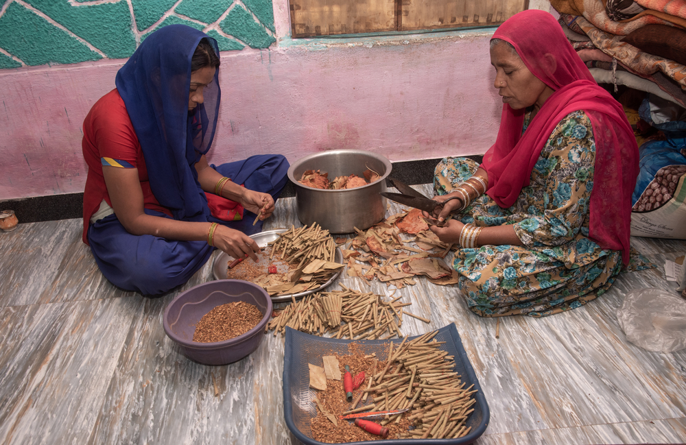 Two women in India rolling Bidi cigarettes on the ground